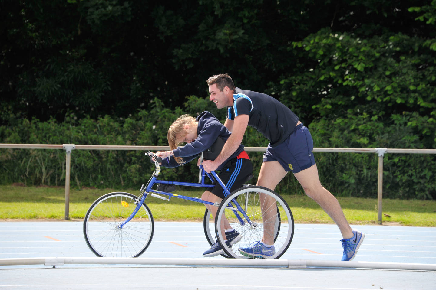 A disabled child race running with support from a teacher