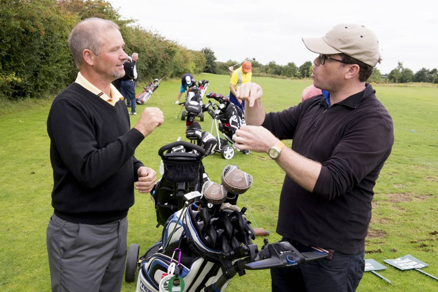 Two deaf golfers chatting while out playing a round of golf.