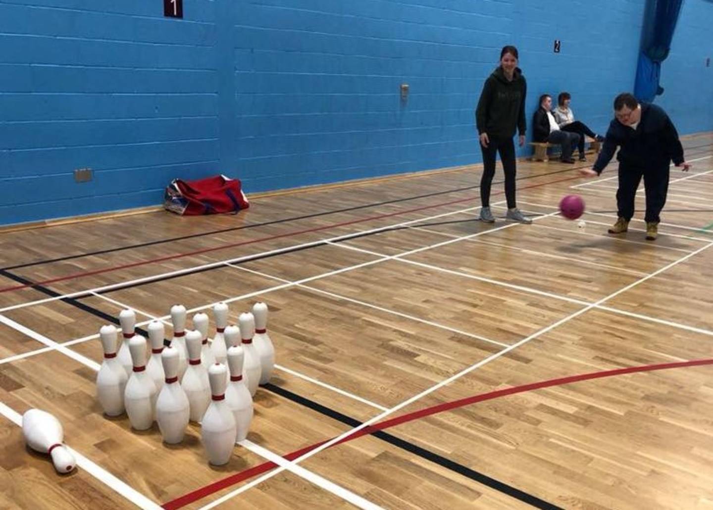 Boy playing skittles in sports hall