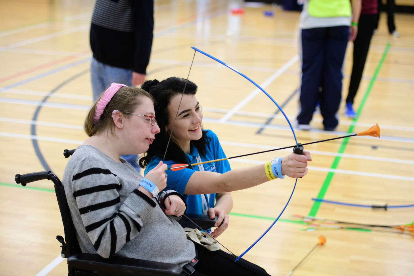 Young woman in a wheelchair taking part in archery with supporter