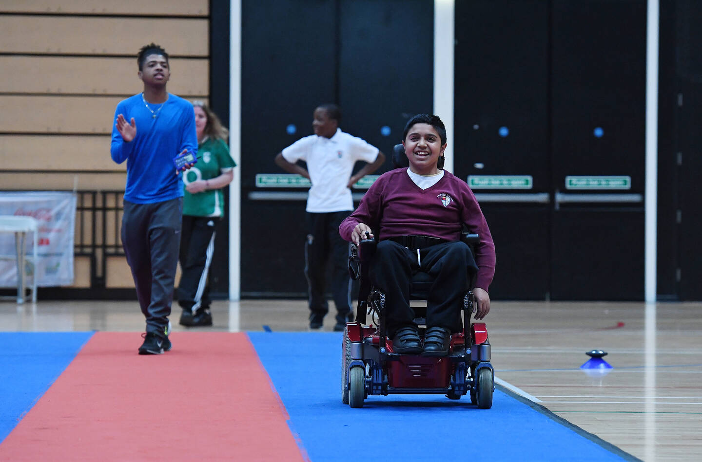 Boy in powerchair taking part in an inclusive relay race at school sports day 