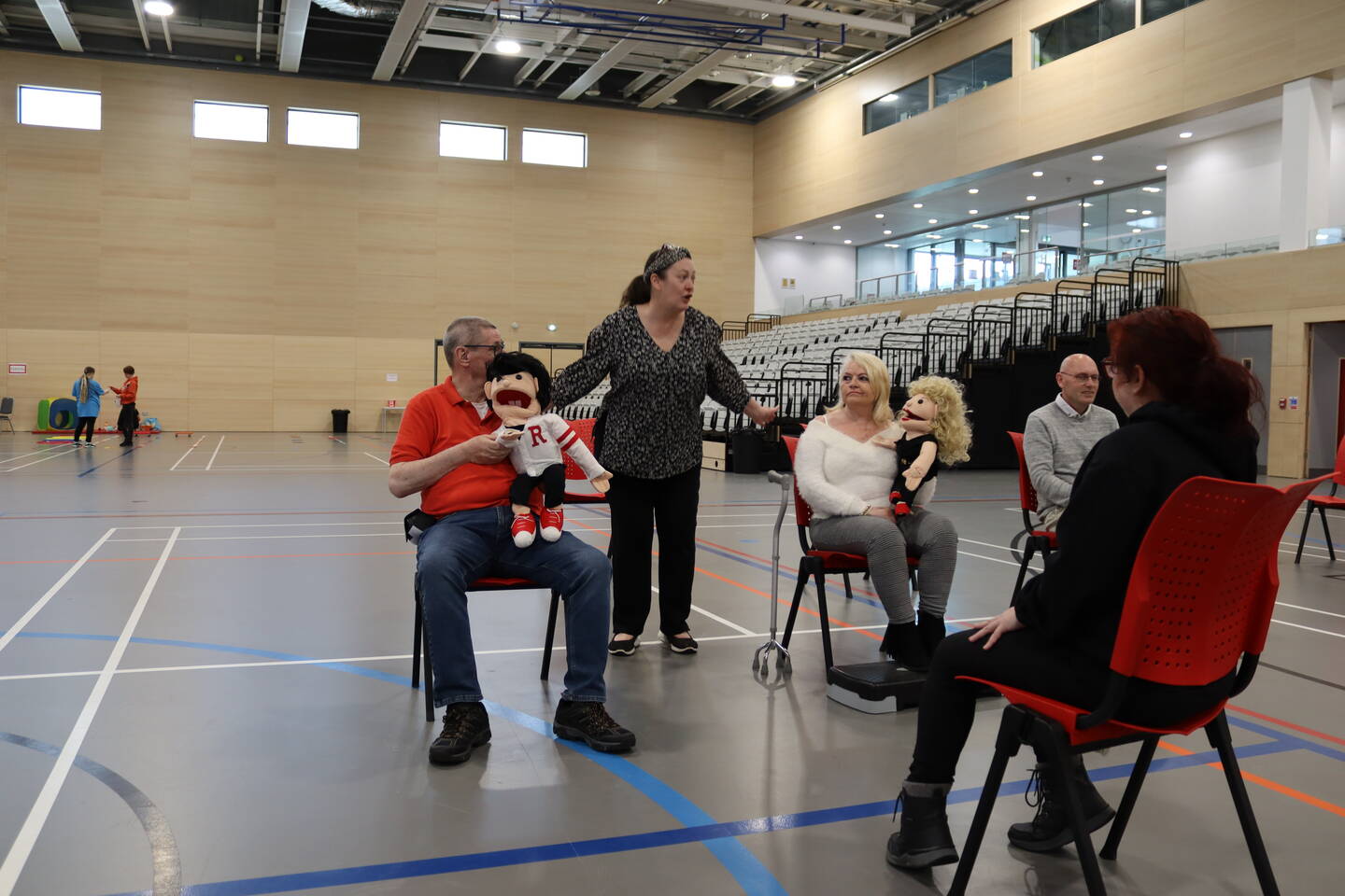 A group of disabled and non-disabled people taking part in seated exercise with puppets. 