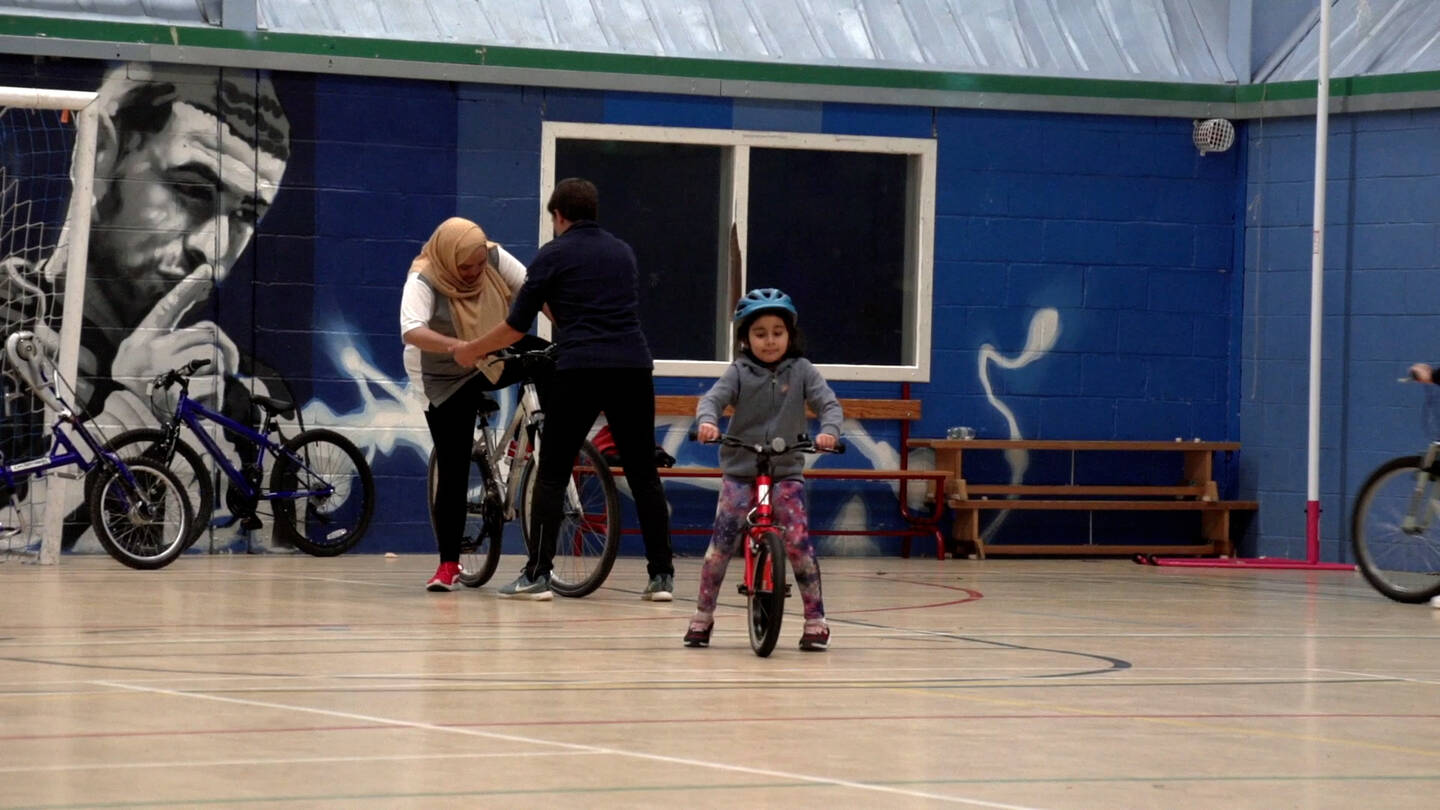 Young girl riding a balance bike in a sports hall
