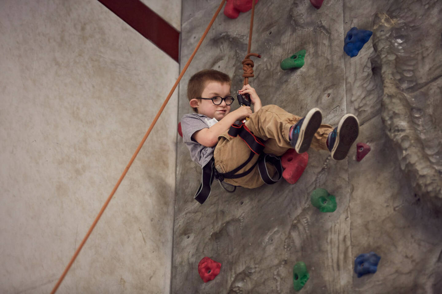 A child on a rope rock climbing.