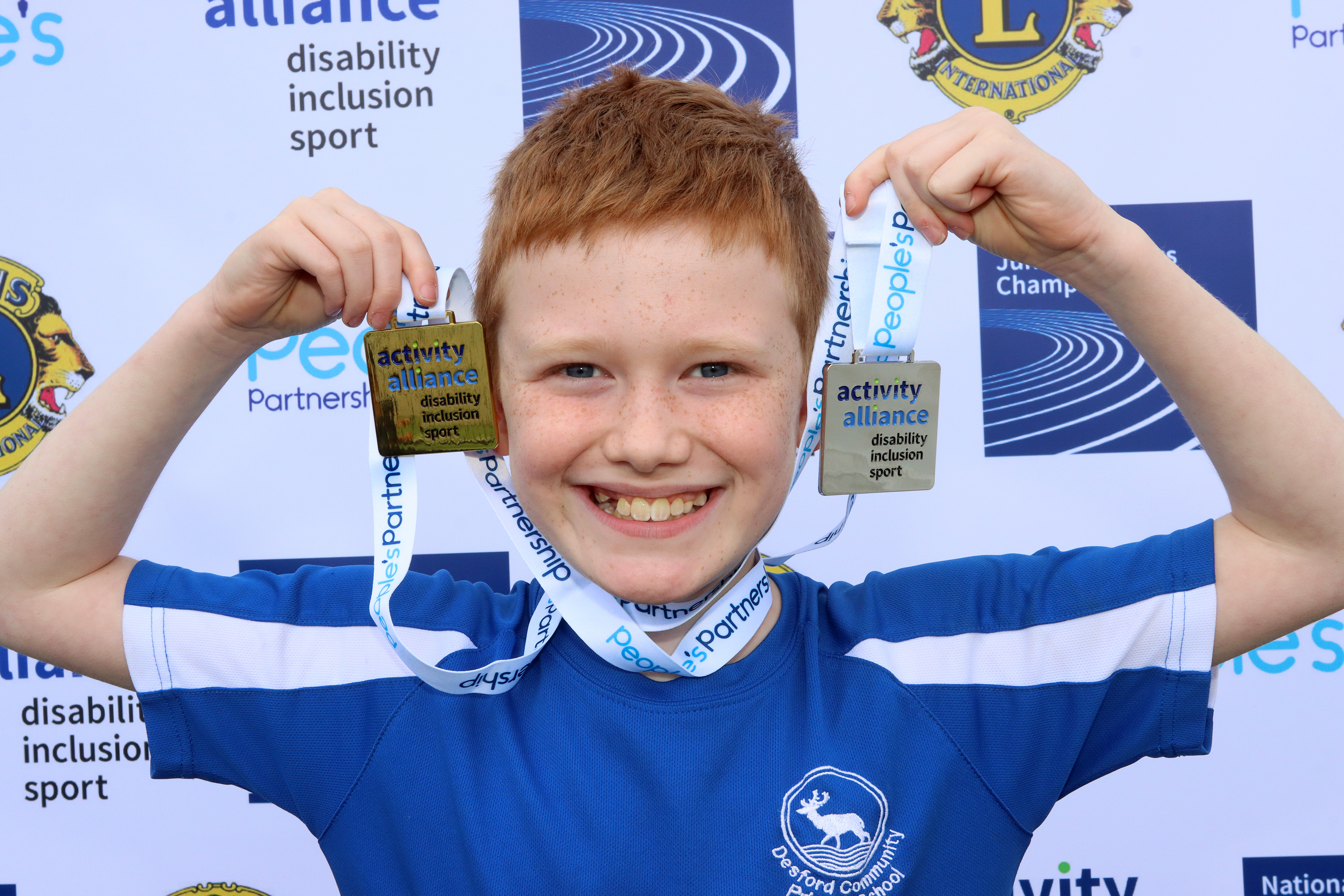 A junior holding up his medals at the 2023 event