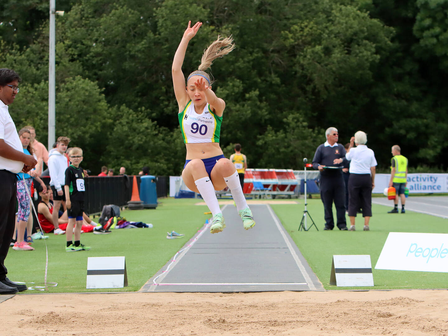 A girl jumps into a sand pit in the long jump at an athletics competition.