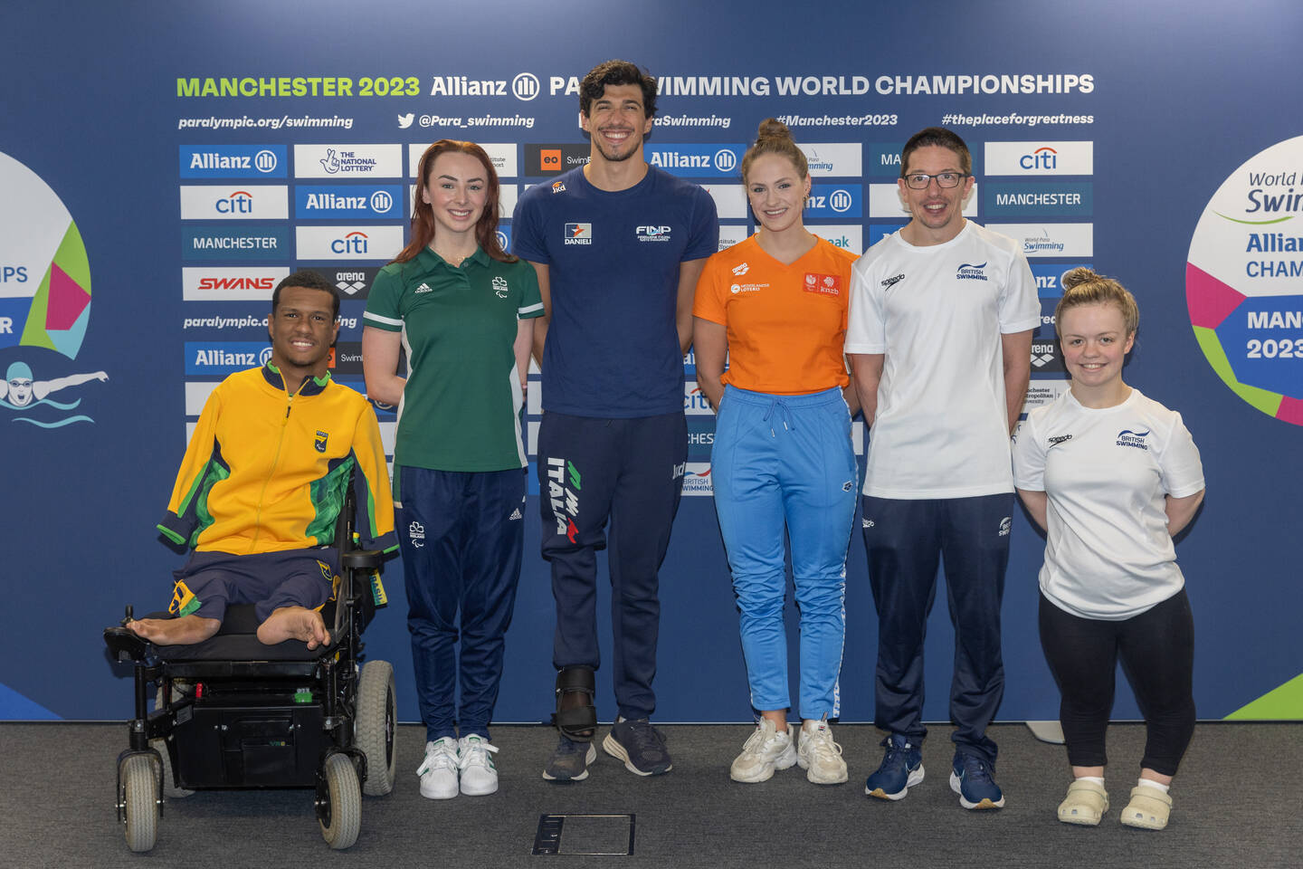 Six swimmers in tracksuits line up in front of a branded Manchester 2023 Allianz Para Swimming World Championships board.

Photo credit:Sam Mellish / Manchester 2023 Allianz Para Swimming World Championships 